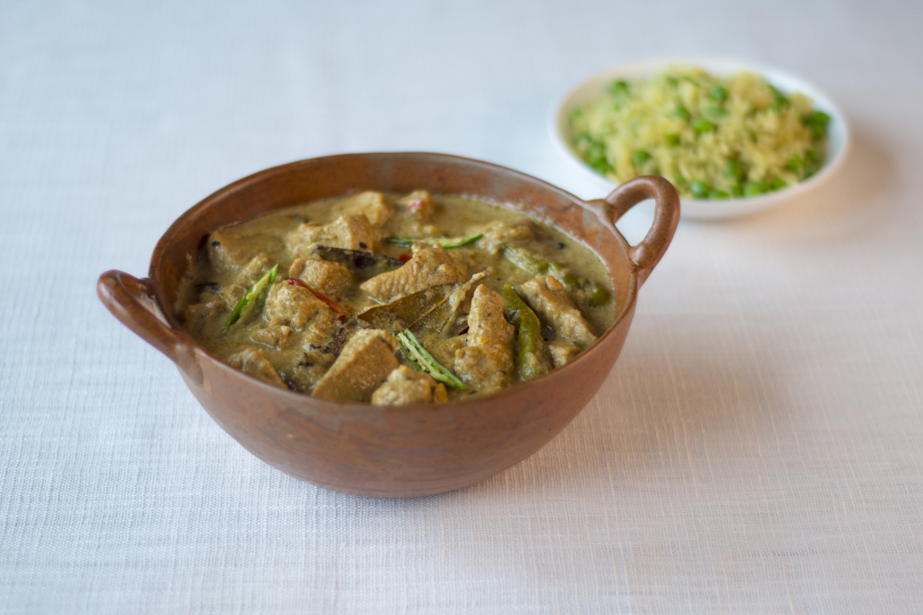 Picture of a bowl of Chicken Korma and a plate of pilau rice with peas.